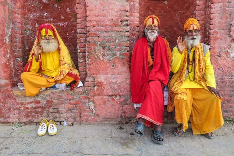 Essential Ingredients That Define Kathmandu’s Cuisine – Travel Guide to Kathmandu 19 three religious men in yellow and red robes sitting by the red brink building