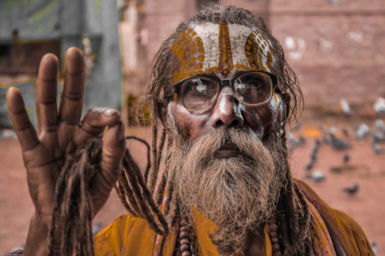 man with paint on face raising right hand