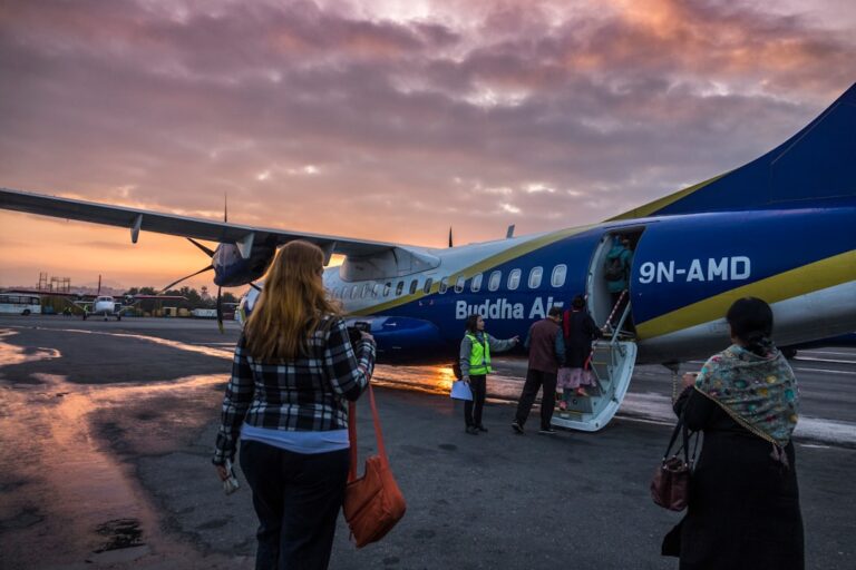 woman in blue denim jacket standing near blue and white airplane during daytime