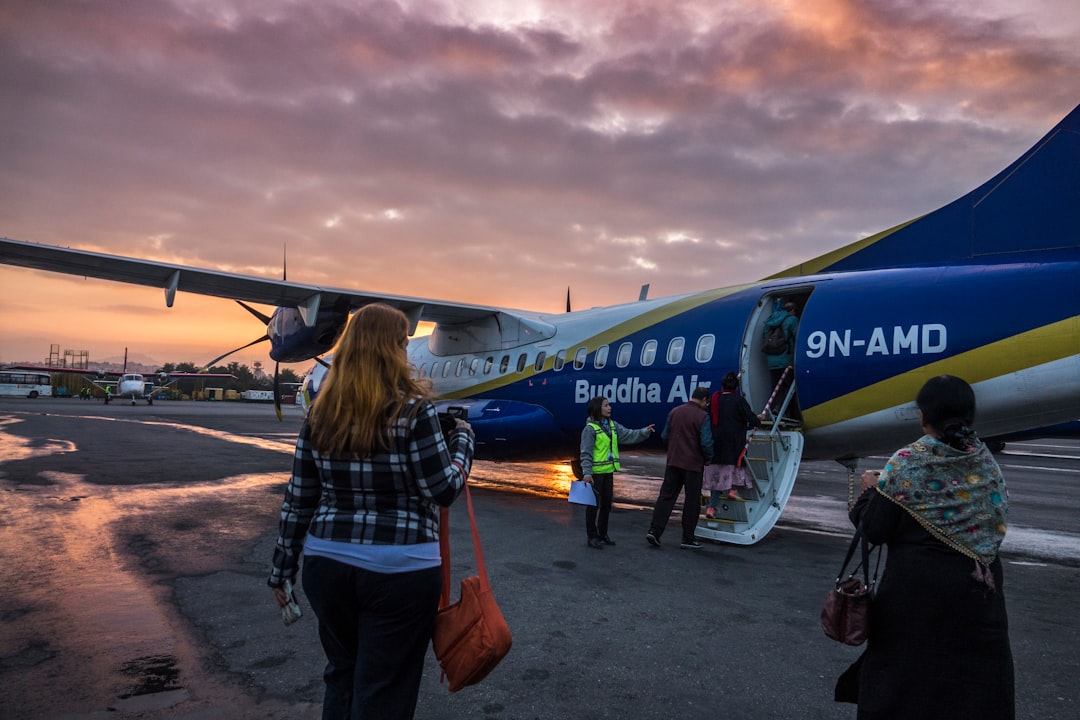 woman in blue denim jacket standing near blue and white airplane during daytime