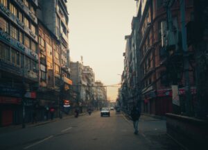 a man walking down a street next to tall buildings
