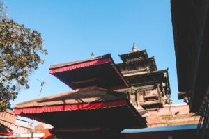 a tall building with a red roof next to a tree