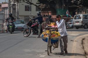 a person pushing a cart full of fruit on a street