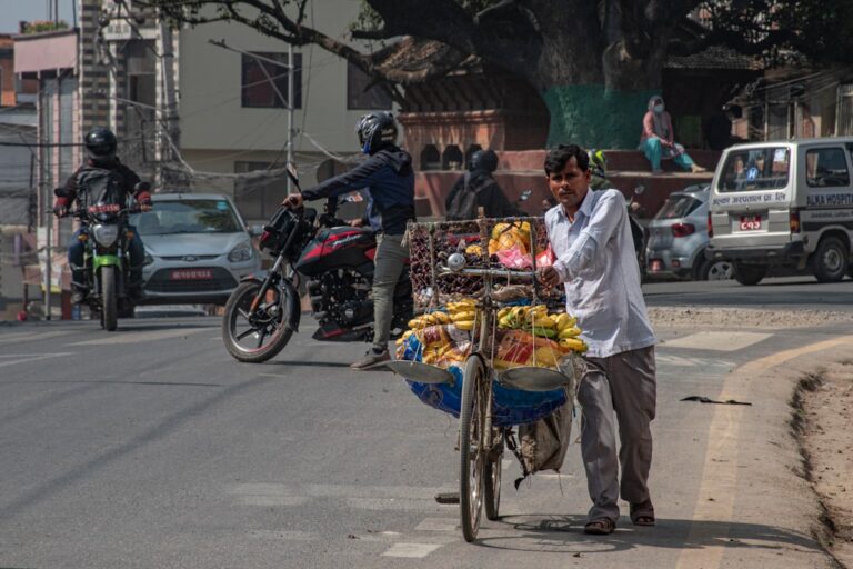 a person pushing a cart full of fruit on a street