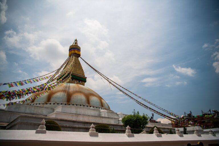 Hidden Historic Gems in Kathmandu – Travel Guide to Kathmandu 16 a large building with a large dome and a large gold tower with Boudhanath in the background