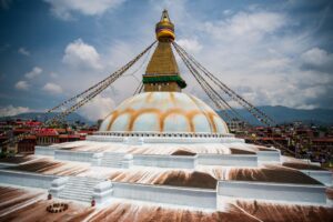 a large domed building with a gold tower and a gold dome with Boudhanath in the background