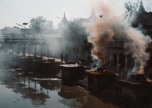 smoke billowing out of a building next to a body of water
