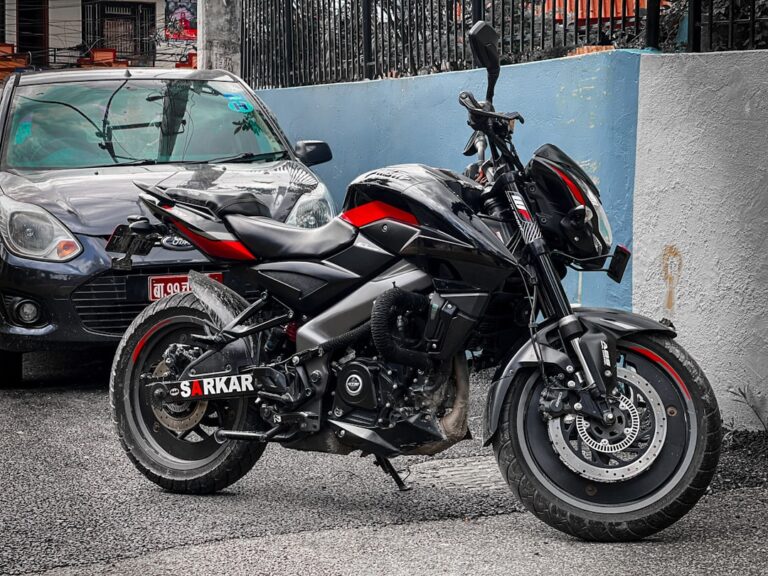 A red and black motorcycle parked next to a car