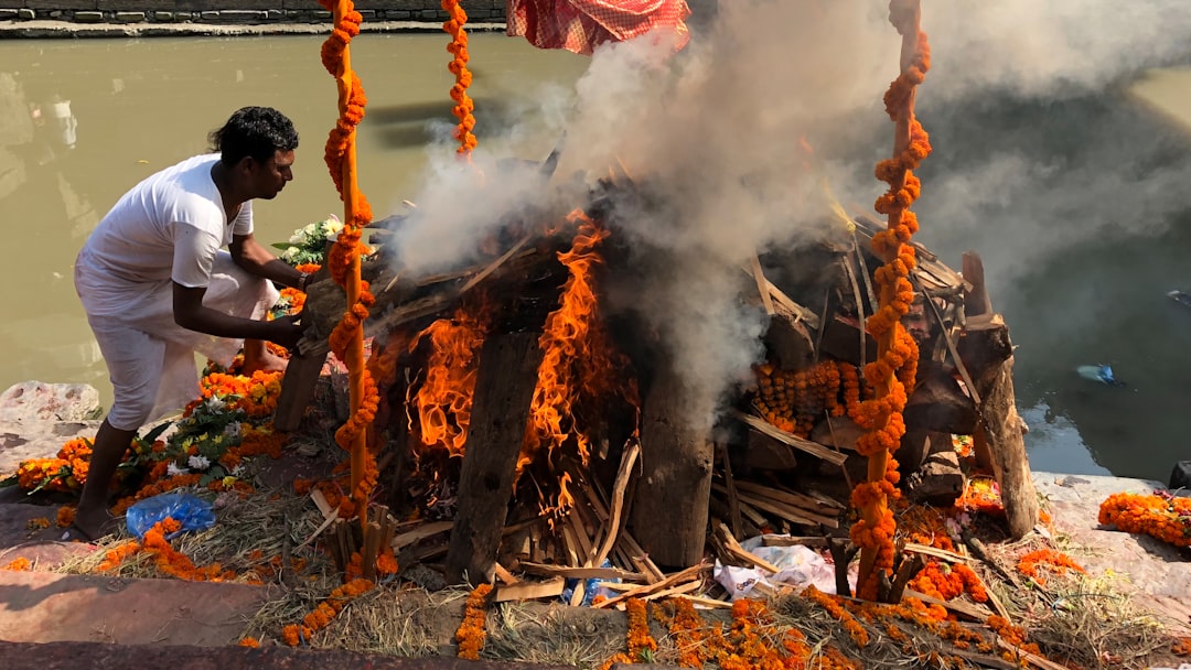 A man standing next to a pile of burning sticks