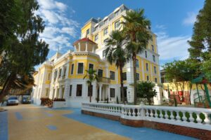 A large yellow building with palm trees in front of it