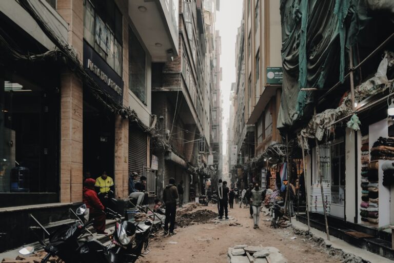 A group of people walking down a street next to tall buildings
