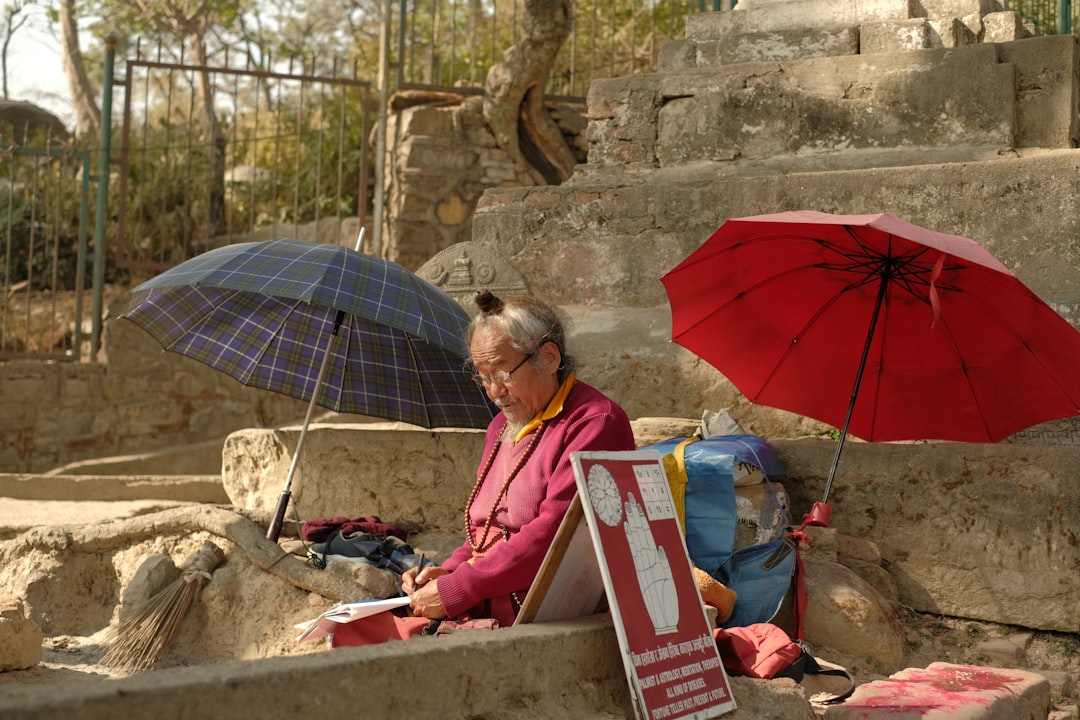 An elderly woman sells items outdoors.