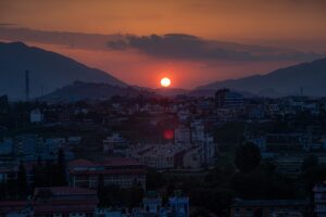 Sunset over a hazy cityscape with mountains