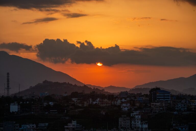 Golden sunset over distant mountains and city lights