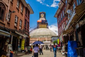 Street view leading to a large stupa with buildings.